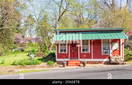 JONESBOROUGH, TN, USA--9 APRIL 2021: Ein hübsches rotes Häuschen mit einem grünen Metalldach in der Innenstadt. Stockfoto