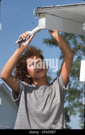 San Antonio, TX, USA: Freiwilliger aus der Mittelschule malt während eines von der Stadt gesponserten „Paint-a-thon“ das Haus eines Einwohners mit niedrigem Einkommen aus. ©Bob Daemmrich Stockfoto