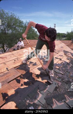 Midland, TX USA: Freiwilliger entfernt abgenutzte Schindeln vom Dach eines einkommensschwachen Hauses während des „Weihnachts im April“-Tages, der von Kirchen in der Region gesponsert wird. ©Bob Daemmrich Stockfoto