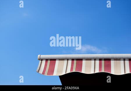 Einlauffähige Markise oder Zelt aus Segeltuch. Sonne- und UV-Schutz-Konzept. Blick in den hohen Winkel. Klarer blauer Himmel. Weiße Wolke. Heißer, klarer Sommertag. Regenfest. Stockfoto