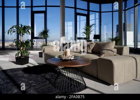 Vorderansicht des schicken Innenraums geräumiges Zimmer mit großem Panoramafenster mit unglaublichem Blick auf die Stadt und gemütlichem grauen Sofa mit Kissen und grünen Blumentöpfen. Konzept der modernen Innenausstattung. Stockfoto