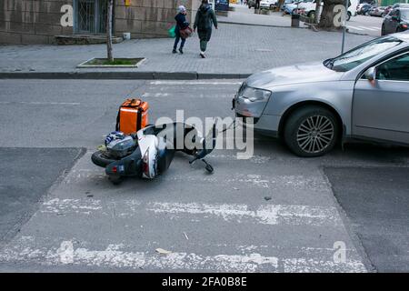 Dnepropetrovsk, Ukraine - 04.21.2021: Helm und Motorrad nach einem gefährlichen Verkehrsunfall mit einem Auto auf der Straße. Der Mann für die Lebensmittelzustellung wa Stockfoto