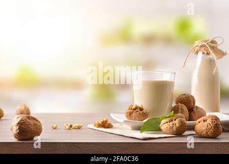 Glas und Flasche alternativen Gemüsegetränk Walnüsse mit Obst auf Holztisch in der Küche Stockfoto