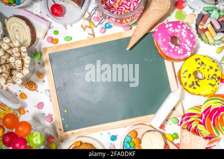 Auswahl an bunten Süßigkeiten. Set mit verschiedenen Süßigkeiten, Pralinen, Donuts, Keksen, Lutschern, Eiscreme von oben auf weißem Hintergrund Stockfoto