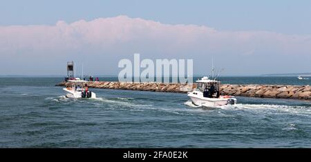 Hampton Bays, New York, USA - 6. Juni 2020: Zwei Motorboote neben einem Felssteg, die nach der Fahrt durch den Shinnecock-Kanal in die Great Peconic Bay fahren Stockfoto