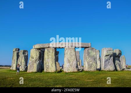 Altes Stonehenge auf der Salisbury Plain in Großbritannien mit einem Nur wenige Touristen drinnen und in der Umgebung gegen einen sehr blauen Himmel Stockfoto
