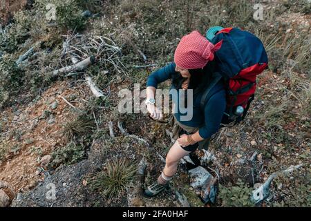 Eine Draufsicht auf eine Backpacker-Frau, die auf eine Uhr schaut. Eine Wanderin, die sich auf eine Reise begibt und die Zeit überprüft. Stockfoto