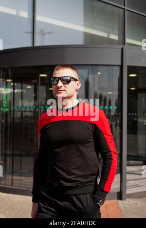 Ein junger, athletischer Mann in einem Trainingsanzug kommt raus Die Drehtüren Stockfoto