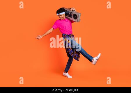 In voller Länge Körpergröße Foto von lockigen Kerl tanzen mit Boom Box auf Party am Wochenende isoliert auf vibrierenden orange Farbiger Hintergrund Stockfoto