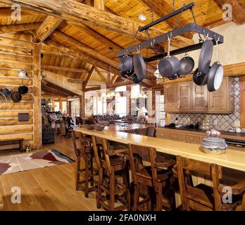 Die Küche mit Theke, Topfablage und rustikalen Schränken, in einer modernen Blockhütte in den Bergen Stockfoto