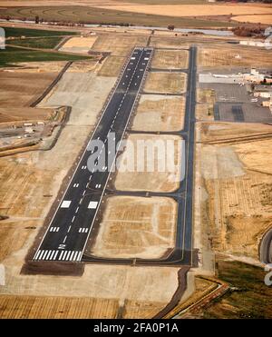 Die Start- und Landebahn, der Rollweg, das Terminal und das Parken von Flugzeugen an den Idaho Falls, dem Flughafen der Stadt Idaho, werden in der Abenddämmerung aufgenommen, um die Landescheinwerfer und Markierungen zu zeigen. Stockfoto