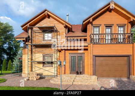 Moderne Holz Öko Haus Villa Fassade während des Prozesses der Renovierung, Schleifwand zum Lackieren gegen Sonnenbrand, Rinde Käfer Feuchtigkeit an Stockfoto