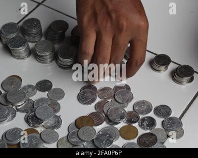 Mann, der indonesischen Penny zählt. Gestapelte Rupiah-Münze. Stockfoto