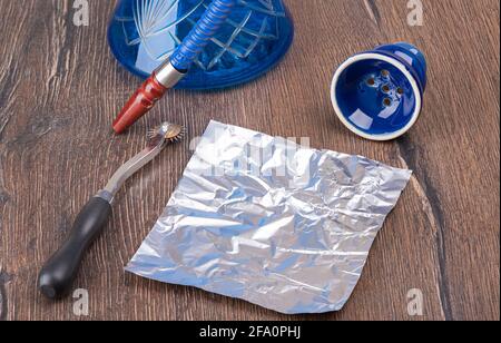 Foil Punch, Foil und Shisha Schale auf einem Holztisch. Shisha-Vorbereitung. Stockfoto