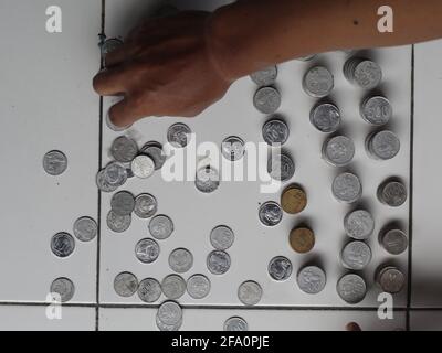 Mann, der indonesischen Penny zählt. Gestapelte Rupiah-Münze. Stockfoto