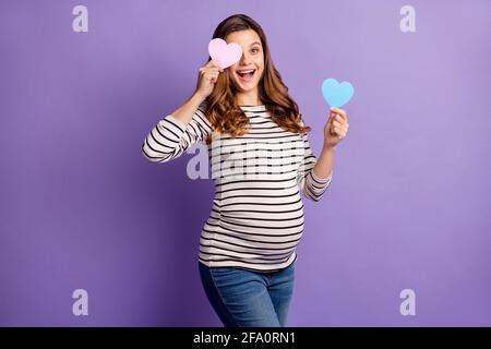 Foto von ziemlich Frau erwartet Kind tragen gestreiftes Hemd Bauch Halten zwei Herzen erraten junge Mädchen isoliert lila Farbe Hintergrund Stockfoto