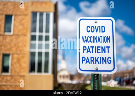 COVID-Impfschild vor dem Krankenhaus mit leeren Plätzen Stockfoto