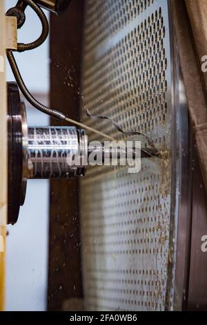 Schwertechnikanlage. CNC-Bohrmaschine. Nahaufnahme der Bearbeitung von Metallteilen. Kühlung des Driil-Werkzeugs durch Wasserstrahl. Petropawlowsk, Kasachstan Stockfoto