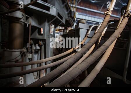 Nahaufnahme von schmutzigen und staubigen geschützten elektrischen Stromkabeln der Maschine.niedrige Schärfentiefe.Schwertechnikanlage Vostokmashzavod,USt'-Kamenogorsk,KZ. Stockfoto