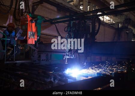 USt'-Kamenogorsk, Kasachstan: Fabrik in Vostokmashzavod. Werkstatt für Schwermaschinenbau. Asiatischer Bediener (links) steuert Schweißmaschine (rechts). Stockfoto