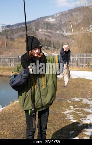 Ein junges Mädchen auf einem Angelausflug mit einer Angelrute und fing Fisch. Zeigt den Fang Stockfoto