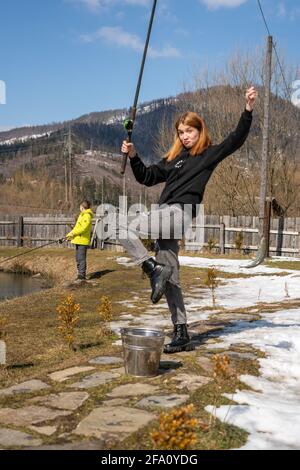 Ein junges Mädchen auf einem Angelausflug mit einer Angelrute und fing Fisch. Zeigt den Fang Stockfoto