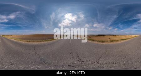 Vollständiges, kugelförmiges, nahtloses Panorama 360 Grad-Ansicht bei No Verkehr alte Asphaltstraße zwischen Feldern mit klarem Himmel und Weiße Wolken in gleicheckig Stockfoto