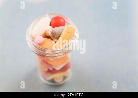 Verschiedene Arzneitabletten in runder Plastikflasche auf grauem Hintergrund Stockfoto