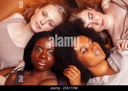 Junge hübsche kaukasische, afro, skandinavische Frau posiert fröhlich zusammen auf braunem Hintergrund, Lifestyle diverse Nationalität Menschen Konzept Stockfoto