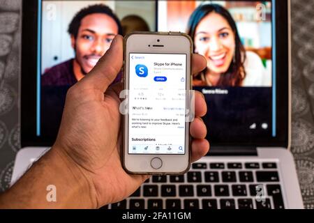 In dieser Abbildung wird eine Skype-App im App Store auf einem Smartphone-Bildschirm angezeigt, während im Hintergrund ein Skype-Desktop auf einem Laptop angezeigt wird. Stockfoto