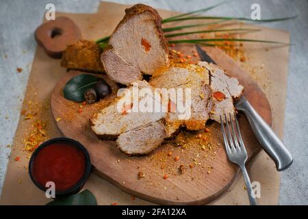 Gebratenes gekochtes Schweinefleisch mit Gewürzen auf einem Holzbrett für Fleisch Stockfoto