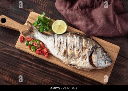Gegrillte dorada mit Chilli, frischem Koriander und Limette auf dem Holzbrett Stockfoto
