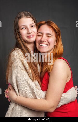 Zwei lächelnde Schwestern umarmten die Halle und schauten auf die Kamera Stockfoto