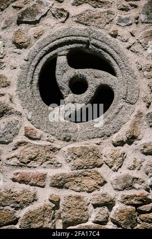 Vertikale Aufnahme einer runden Fensterstruktur auf dem Stein Wand Stockfoto