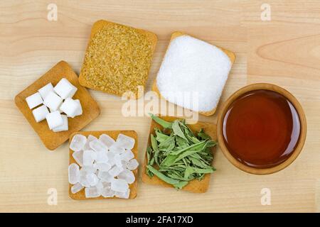 Zuckerwürfel, braune Zuckerkristalle, granulierter Weißzucker, Steinzucker, Stevia, Honig, verschiedene Süssentypen, Draufsicht auf Holzhintergrund Stockfoto