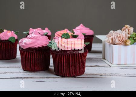 Nahaufnahme eines roten Samtkuchens mit rosa Buttercreme (Seitenansicht). Stockfoto