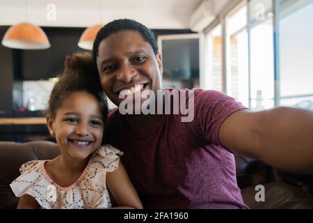 Tochter und Vater nehmen ein Selfie zu Hause. Stockfoto
