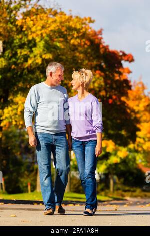 Älteres Paar, Mann und Frau, mit einem Spaziergang im Herbst oder im Herbst im Freien, zeigen die Bäume bunte Laub Stockfoto