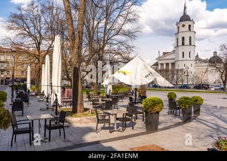 Vilnius hat Bars und Restaurants nach der Sperre wegen Covid oder Coronavirus wieder geöffnet, Tische, Stühle und Sonnenschirme mit dem Turm der Kathedrale im Hintergrund Stockfoto