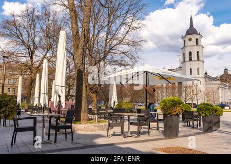 Vilnius hat Bars und Restaurants nach der Sperre wegen Covid oder Coronavirus wieder geöffnet, Tische, Stühle und Sonnenschirme mit dem Turm der Kathedrale im Hintergrund Stockfoto