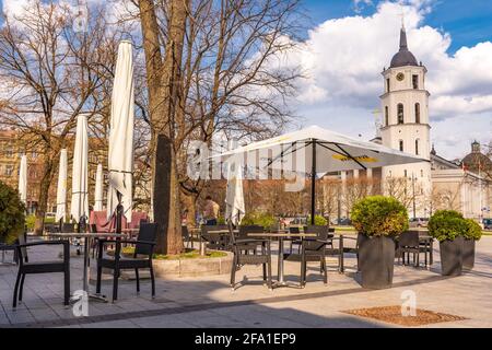 Vilnius hat Bars und Restaurants nach der Sperre wegen Covid oder Coronavirus wieder geöffnet, Tische, Stühle und Sonnenschirme mit dem Turm der Kathedrale im Hintergrund Stockfoto