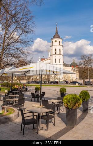 Vilnius hat Bars und Restaurants nach der Sperre wegen Covid oder Coronavirus wieder geöffnet, Tische, Stühle und Sonnenschirme mit dem Turm der Kathedrale im Hintergrund Stockfoto