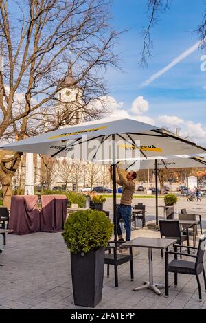 Vilnius hat Bars und Restaurants nach der Sperre wegen Covid oder Coronavirus wieder geöffnet, Tische, Stühle und Sonnenschirme mit dem Turm der Kathedrale im Hintergrund Stockfoto