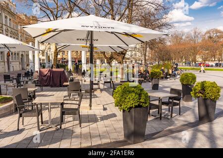 Vilnius hat Bars und Restaurants nach der Sperre wegen Covid oder Coronavirus wieder geöffnet, Tische, Stühle und Sonnenschirme mit dem Turm der Kathedrale im Hintergrund Stockfoto