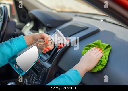 Frau Reinigung ihres Auto-Cockpit mit Spray und Mikrofaser Tuch. Leere weiße Etikett auf einer Sprühflasche. Copy Space Stockfoto