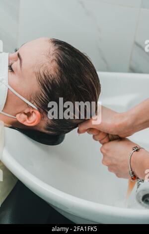 Spülen von Haaren nach Shampoo, Haarpflege im Friseursalon, Besuch des Friseurs während der Quarantäne. Neu Stockfoto