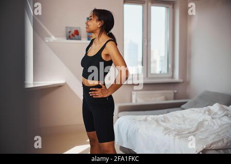 Sportliche junge Frau, die zu Hause im Wohnzimmer steht Stockfoto