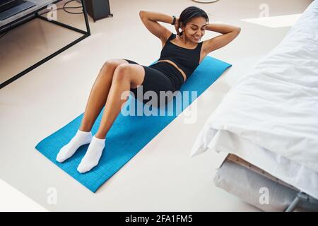 Fröhliche junge Frau tut Bewegung für abs zu Hause Stockfoto