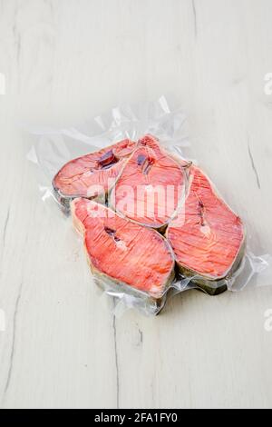 Overhead-Ansicht von rohem Lachssteak in Vakuumverpackung auf Heller Hintergrund Stockfoto