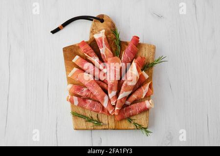 Draufsicht auf gerollte Scheiben von Jamon auf Holzschnitt Platine Stockfoto